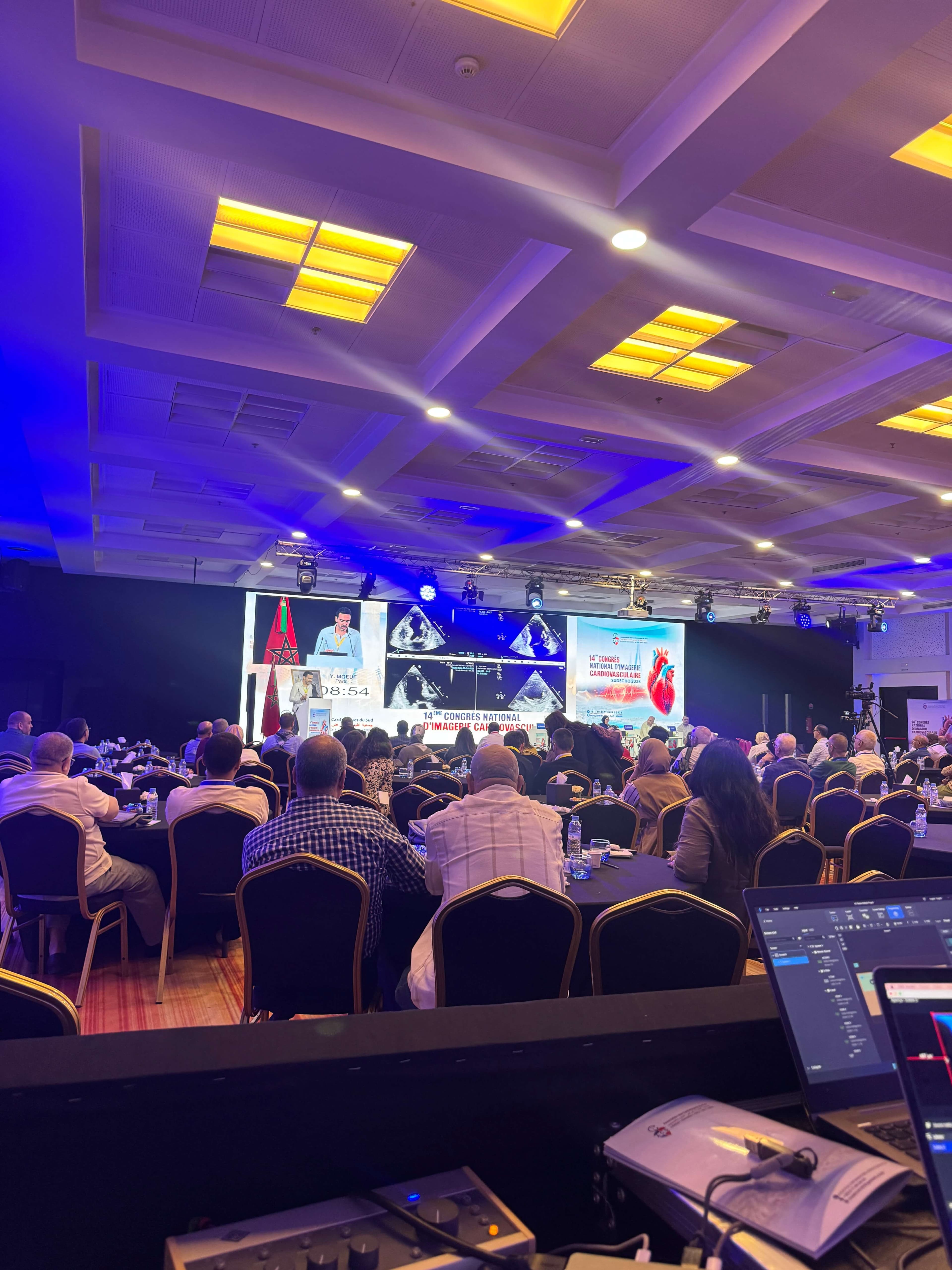 Speaker on stage at a congress, framed by LED screens and stage lighting