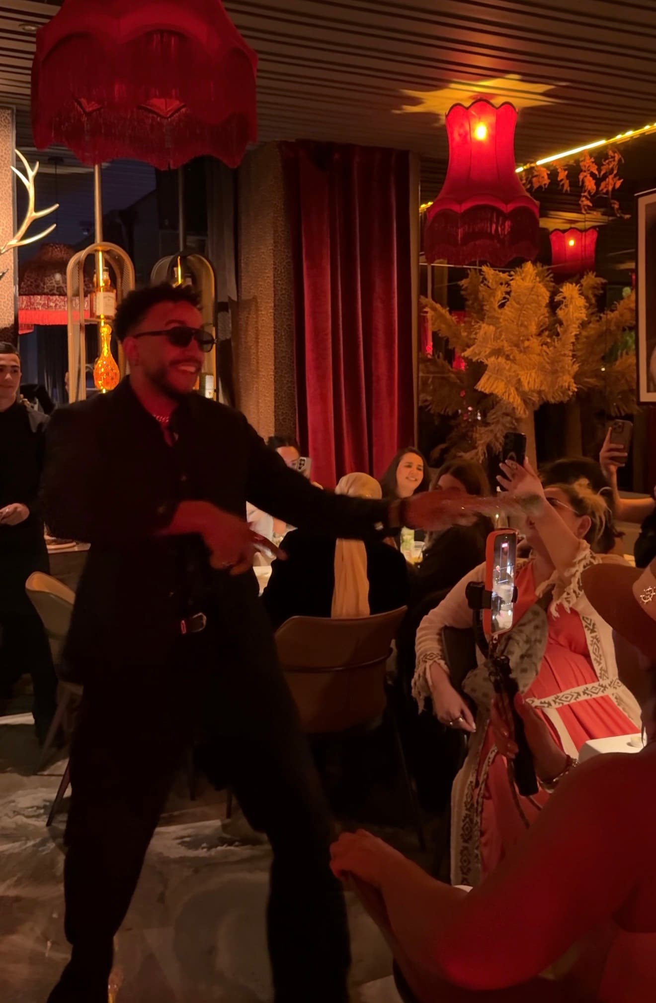 Live singer performing among guests beneath red lampshades